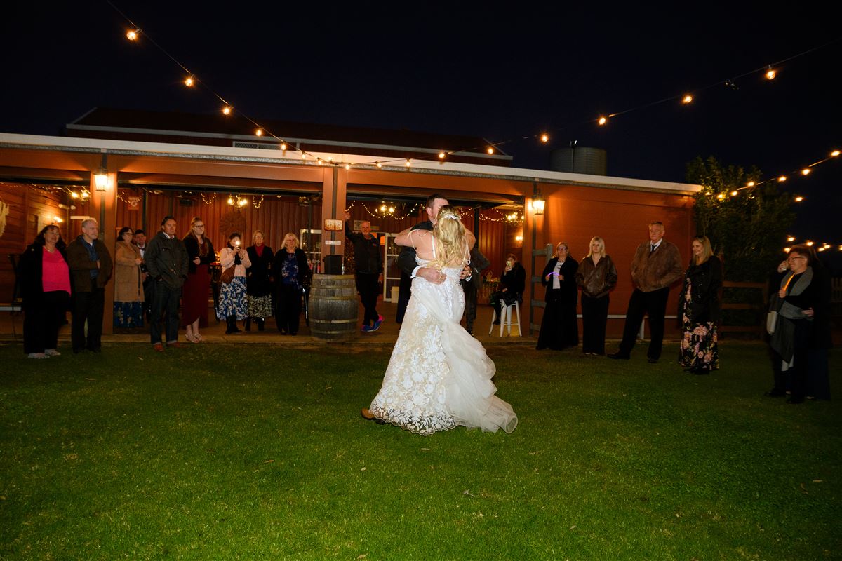 First dance under festoon lights watched by guests