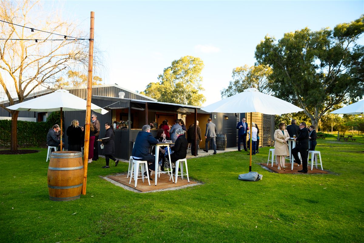 Guests mingling at the outdoor bar under umbrellas