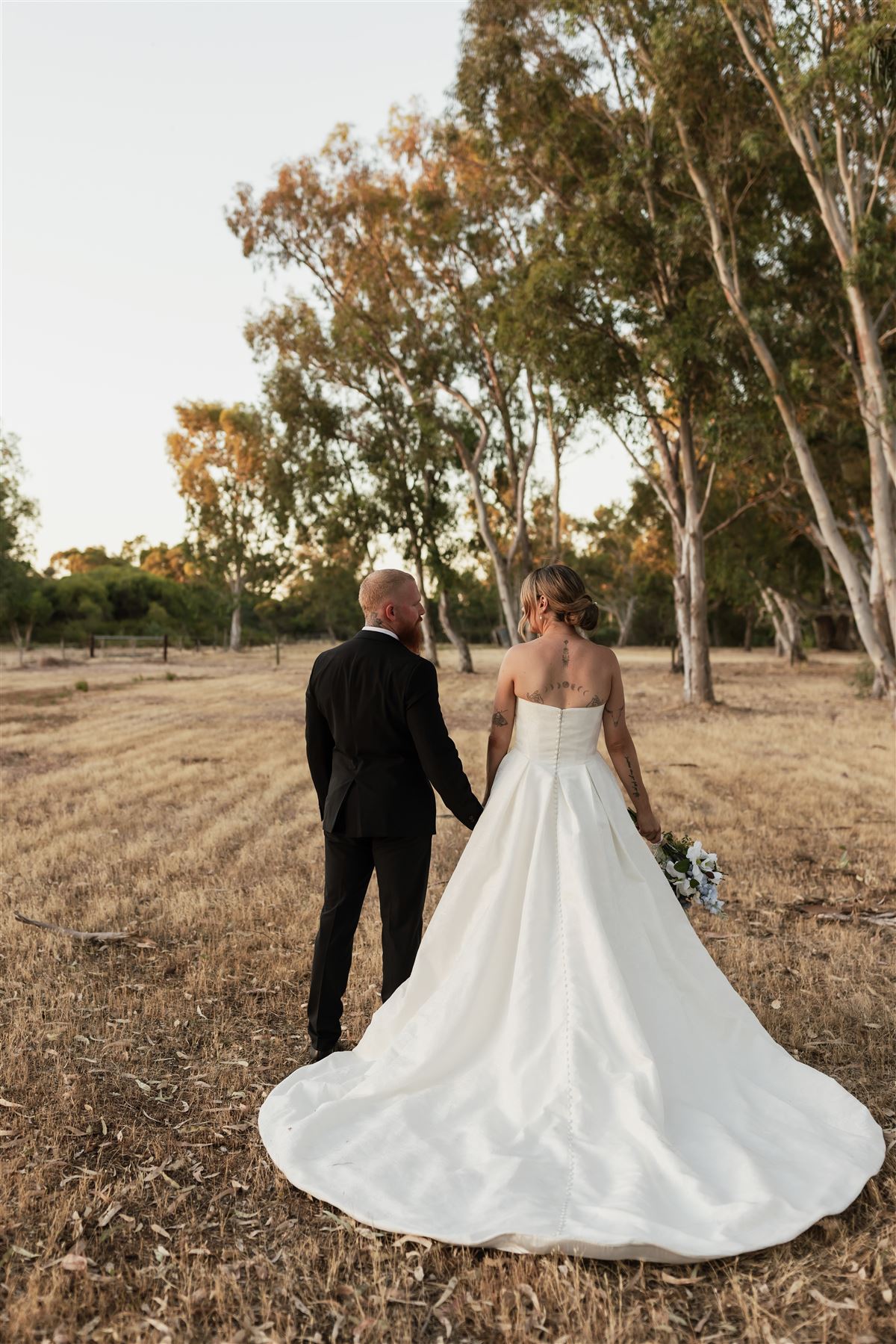 Newlyweds holding hands in the golden Hopeland paddock