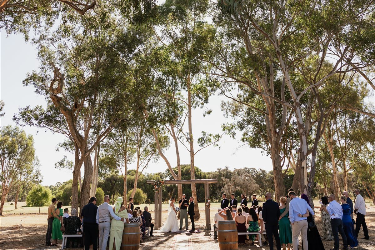 Outdoor wedding ceremony under the timber arbor with guests at The Barn Hopeland